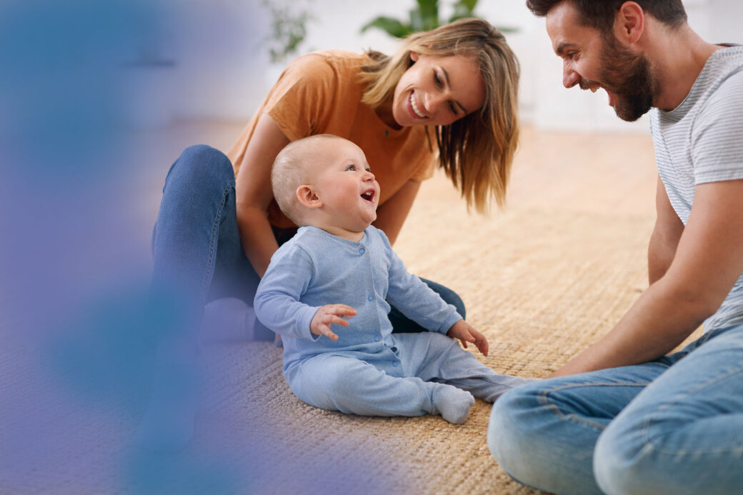Fröhliche Familie im modernen Wohnzimmer. Am Rand des Bildes ist ein violett/blauer Verlauf